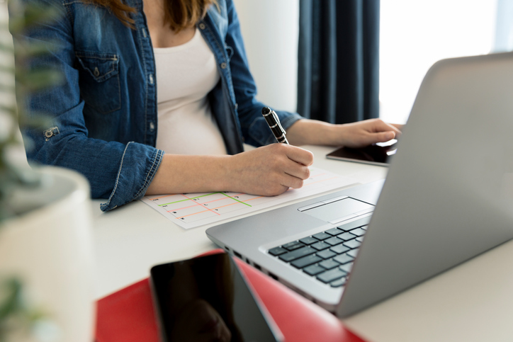Calendar planner agenda schedule concept. Woman working in her office, working, planning. Maternity leave planning