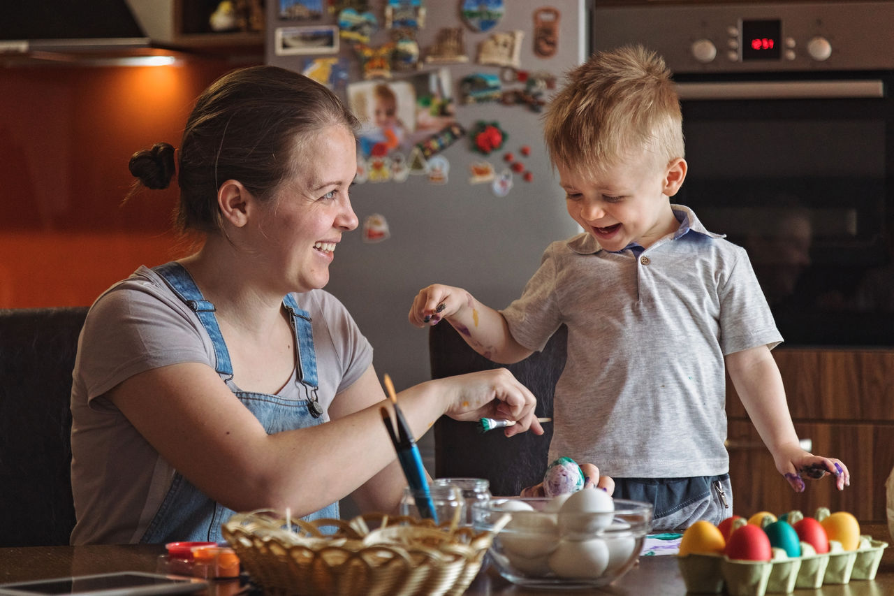 Little boy painting easter eggs with his mother