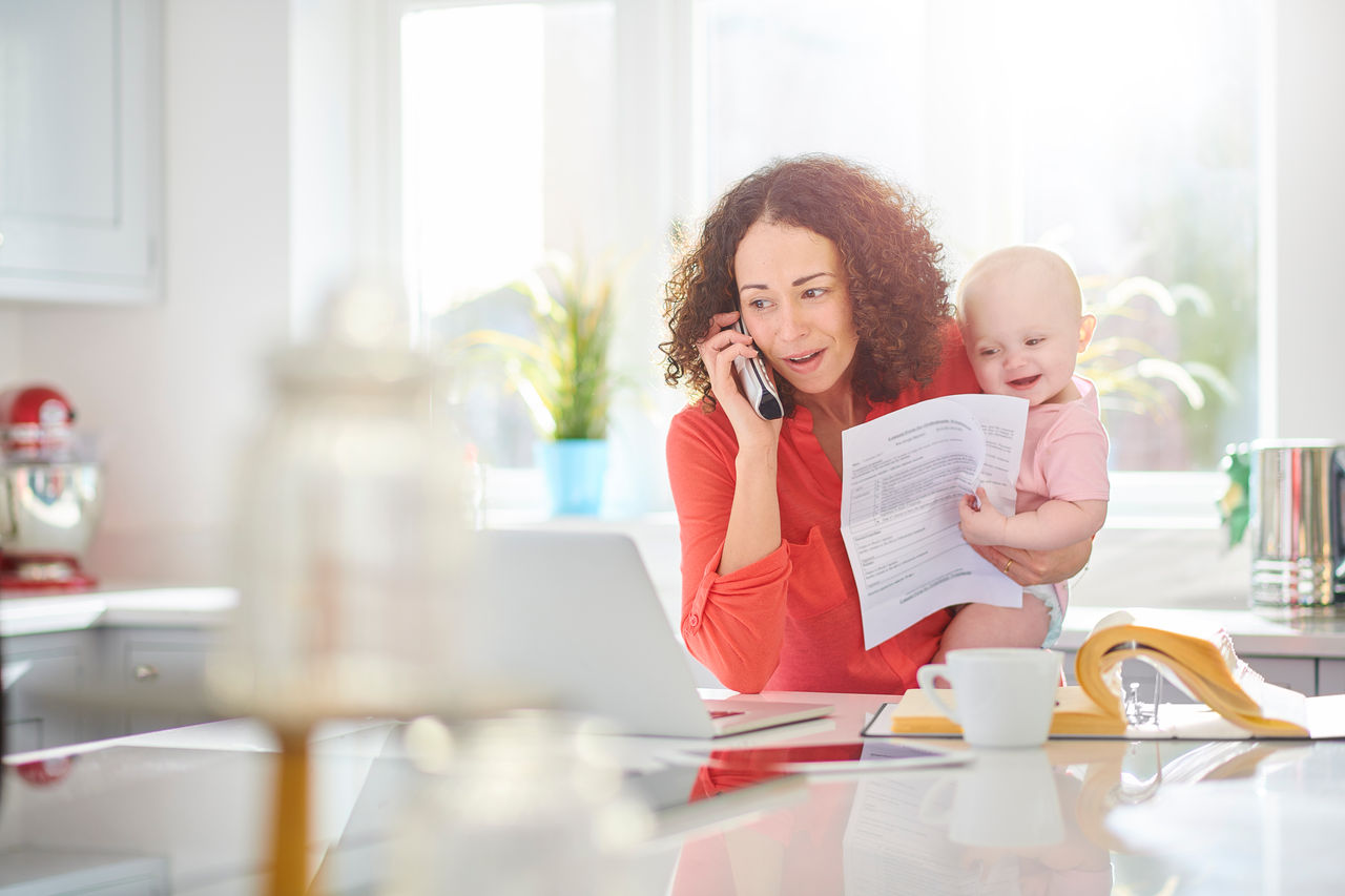 a woman  in her kitchen paying a bill by phone