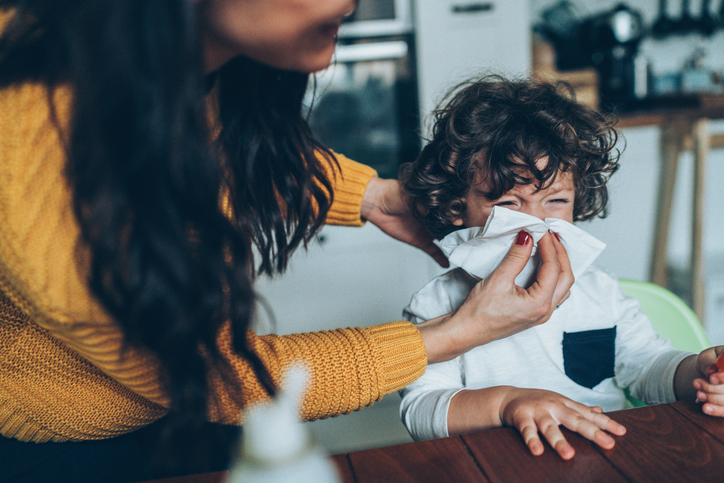 Mother helping son to blow his nose at home