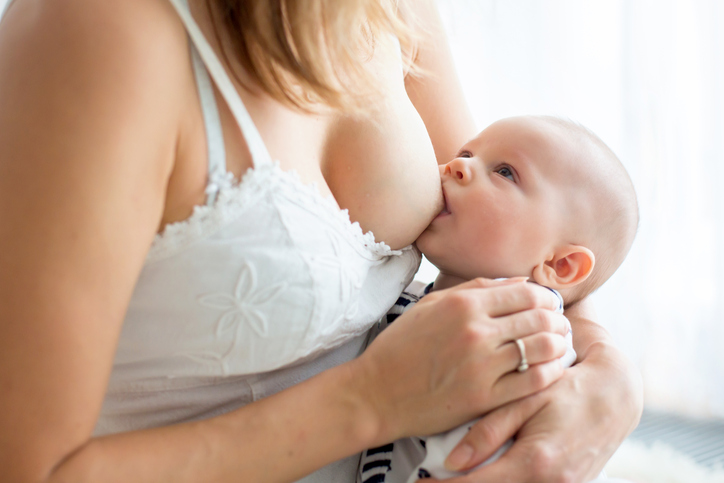 Young mother breastfeeding her newborn baby boy at home
