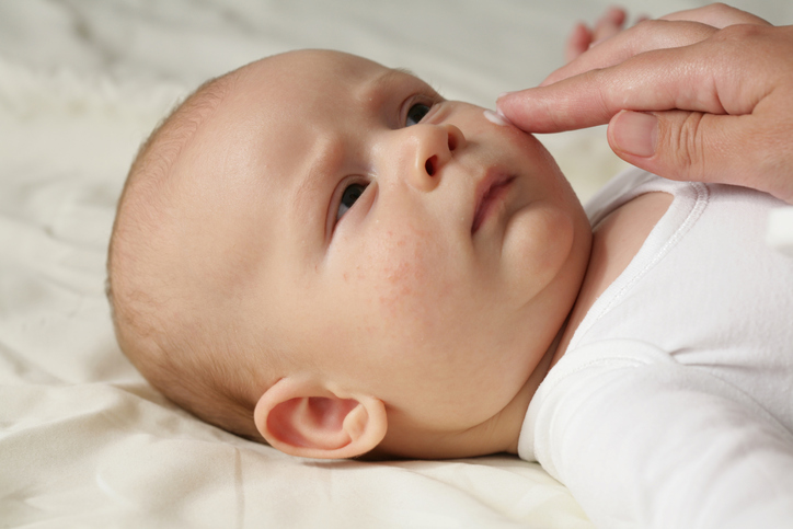 Female hand applying the cream on baby's face