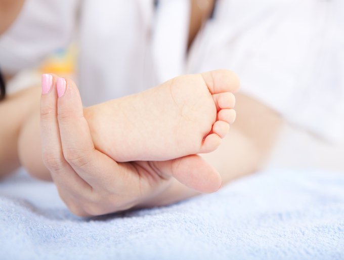 Baby's feet in pediatrician hand - massaging