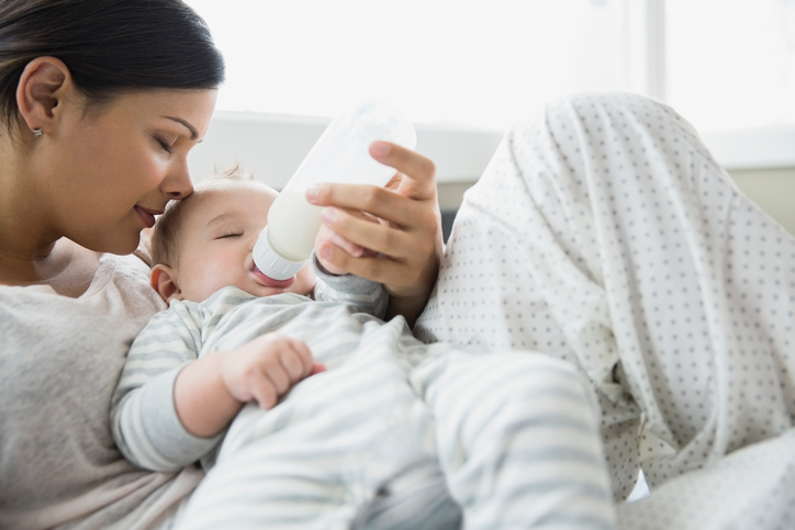 Serene mother feeding baby on bed