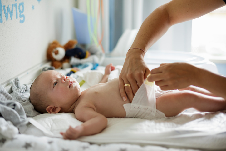 Mothers hand checking looseness of baby sons diaper